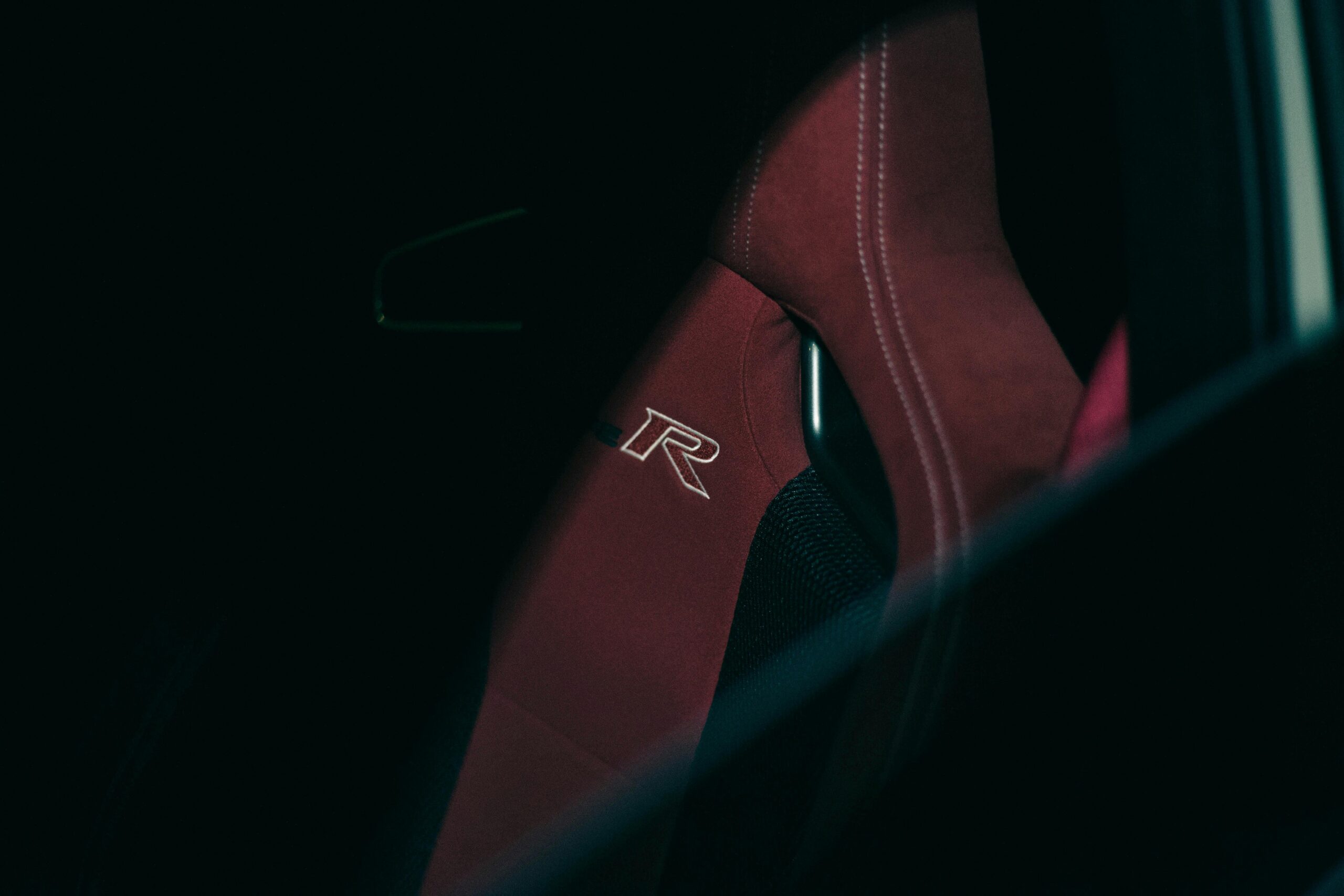 A deep red car seat featuring a logo, captured in low light for a luxurious feel.